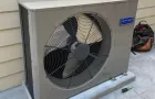 An outdoor HVAC unit sitting on a concrete pad next to a beige-siding wall.